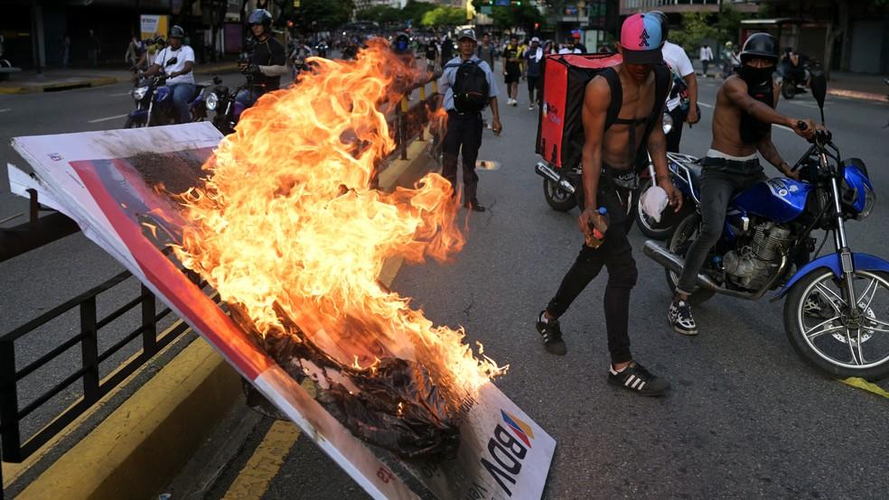 Manifestantes queimam banner durante protesto em Caracas