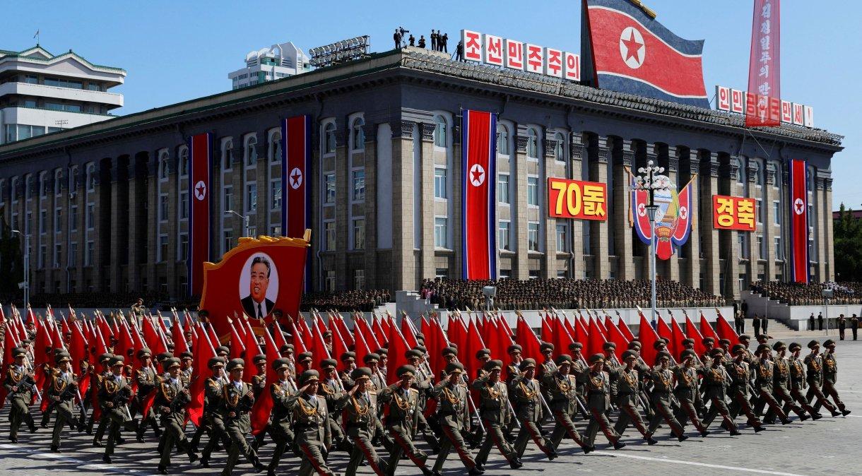 Soldados marcham com o retrato do fundador norte-coreano Kim Il Sung em desfile militar.