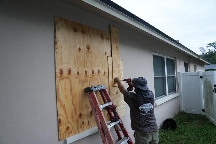 Morador protege janelas com tábuas antes da chegada do furacão Milton em Palm Harbor, na Flórida.