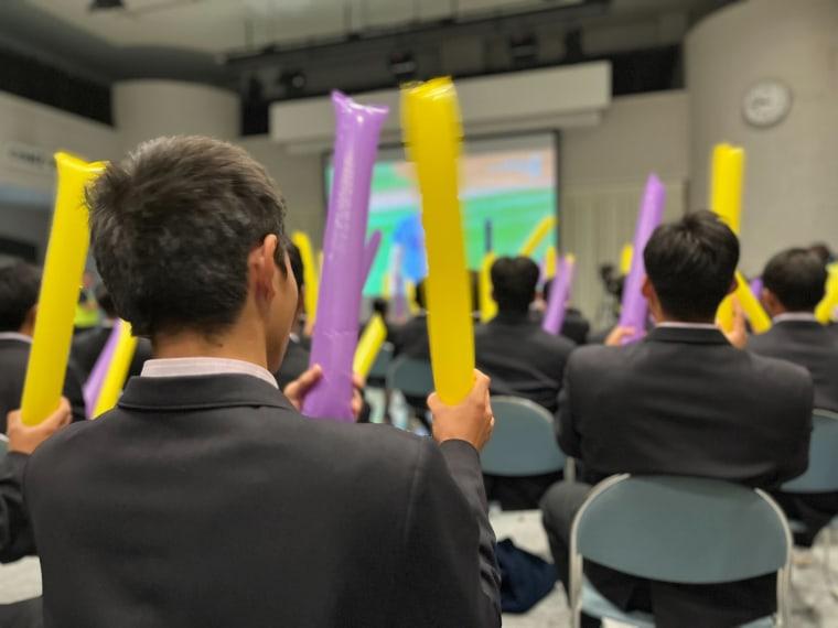 Students hold inflatable balloons while watching the world series