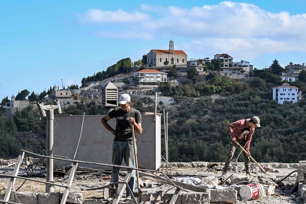 Homens limpam destroços em local de bombardeio israelense na cidade de Aito, no Líbano