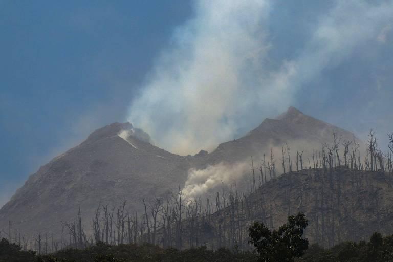 Monte Lewotobi em erupção, com fumaça e vegetação queimada