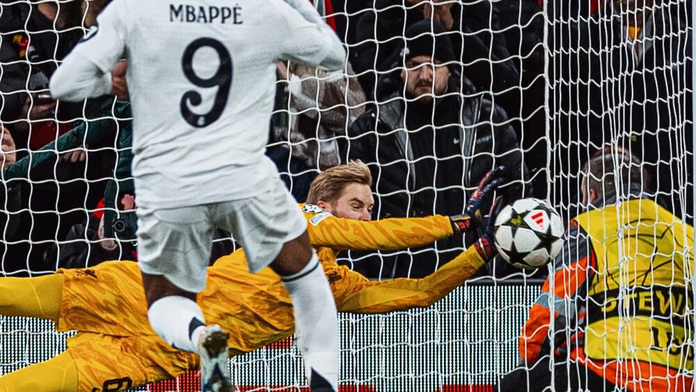 Caoimhín Kelleher, goleiro do Liverpool, defende pênalti de Kylian Mbappé, atacante do Real Madrid.