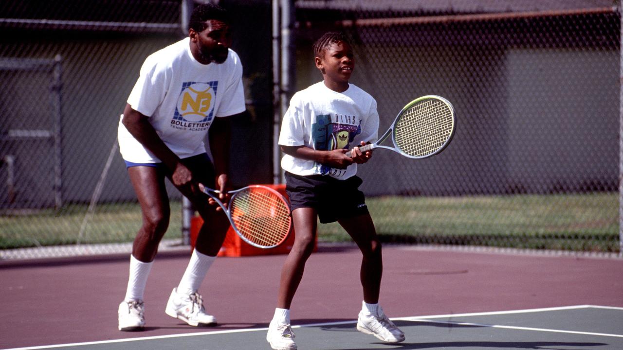 Richard Williams com suas filhas, Venus e Serena, em quadra de tênis.