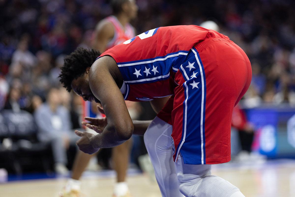 Joel Embiid segurando o rosto após colisão durante o jogo