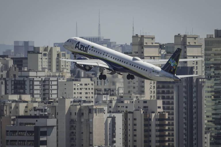 Avião decolando em direção ao céu, com uma cidade ao fundo