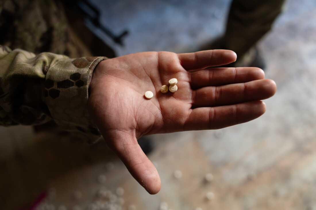 A soldier with the HTS shows some of the Captagon pills that they found at the facility.