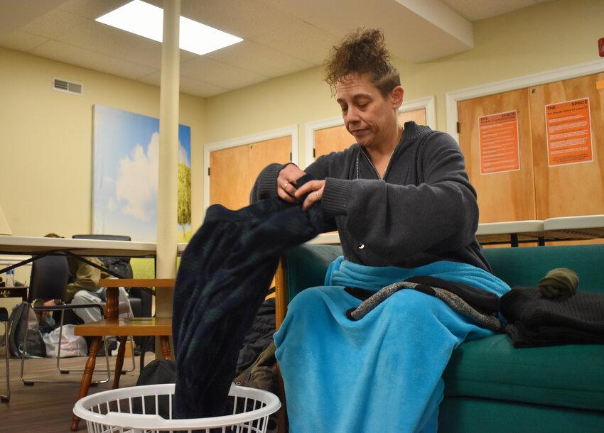 Kim Clark dobra roupas que acabou de lavar na Grace Space em Cortland, um espaço que oferece apoio a pessoas sem-teto.