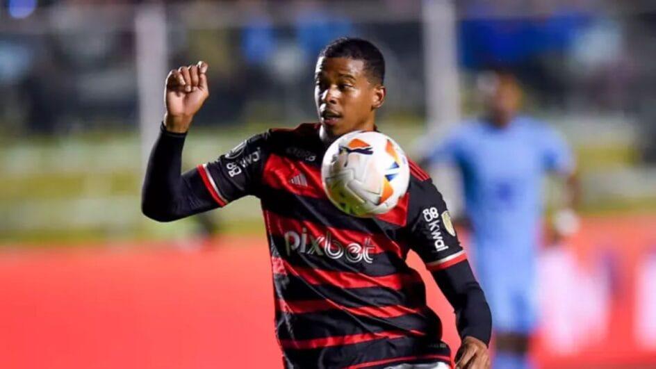 Carlinhos com a camisa do Flamengo e uma bola em frente ao escudo.