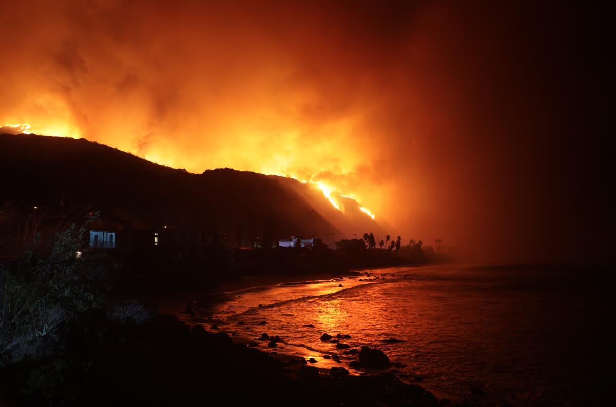 O incêndio Palisades brilha laranja sobre Malibu.