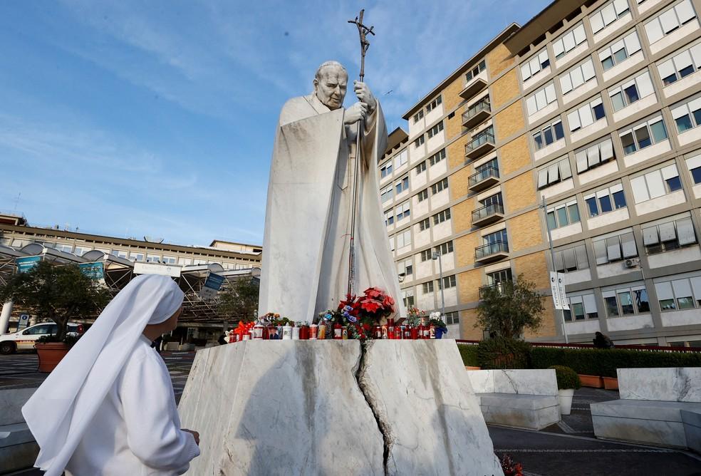 Flores e velas deixadas aos pés de estátua de João Paulo II