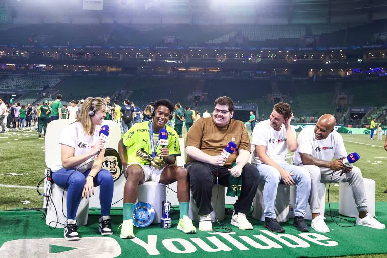 Grupo de pessoas em um evento esportivo, conversando e segurando um troféu