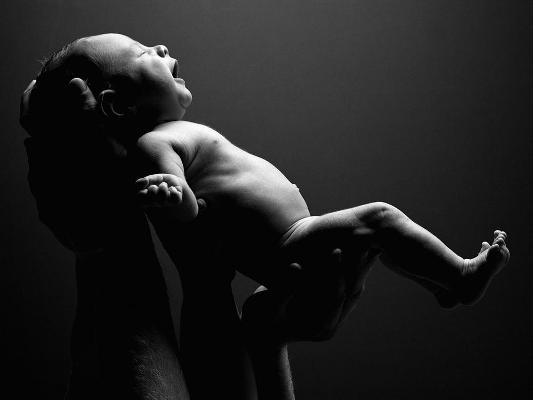 imagem em preto e branco de mãos segurando um bebê