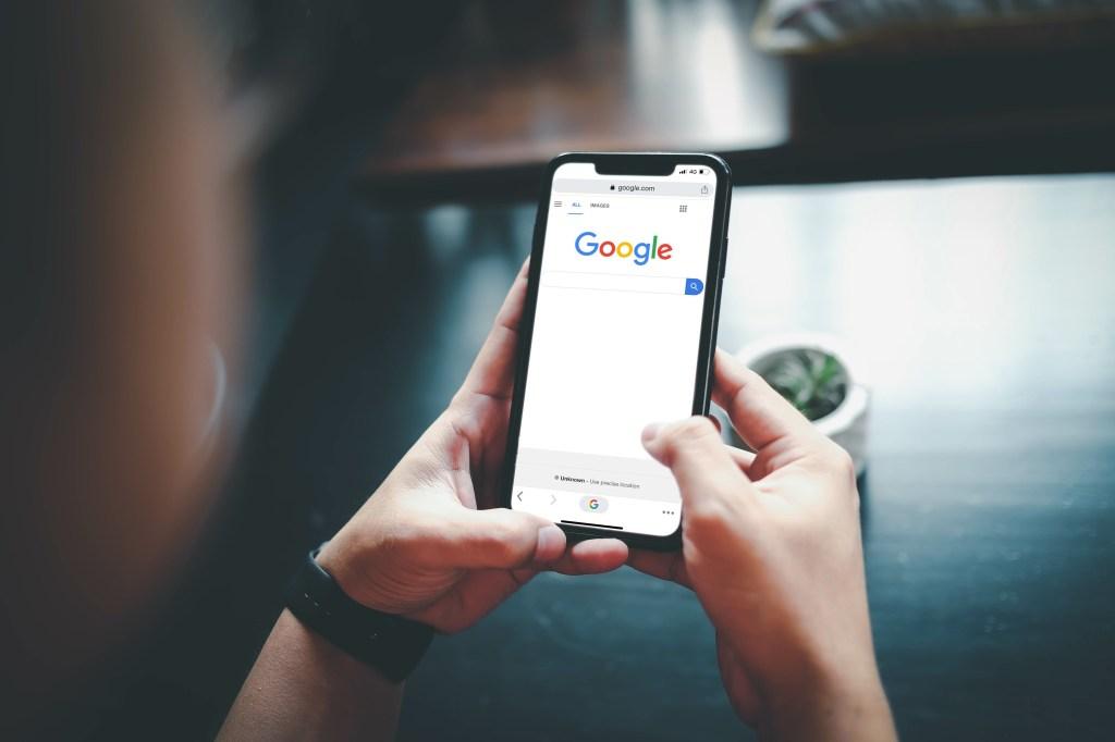 Mulher digitando no Google com um iPhone.