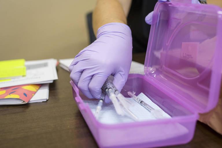 Mão com luvas segurando seringa