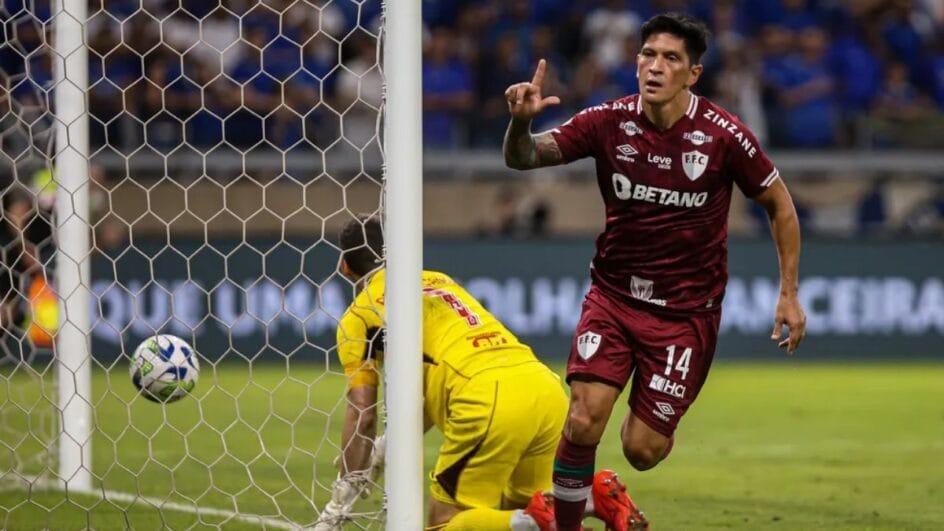 Cano comemorando fazendo o L com a mão e vestindo camisa listrada do Fluminense