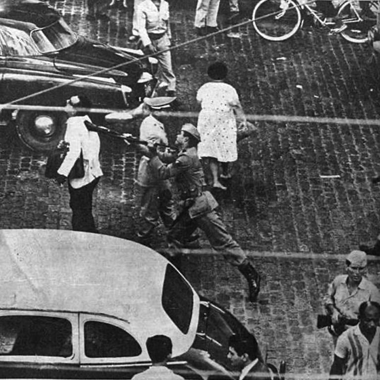 Conflito urbano durante o golpe de 1964 onde um policial agride um homem em Recife.