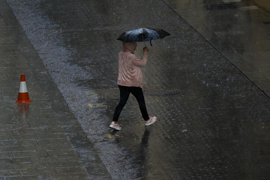 Pessoa se protegendo da chuva em Valência