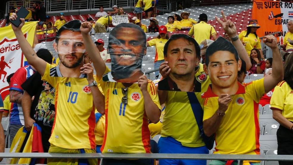 Torcida da Colômbia com máscara de Jhon Arias e James Rodríguez
