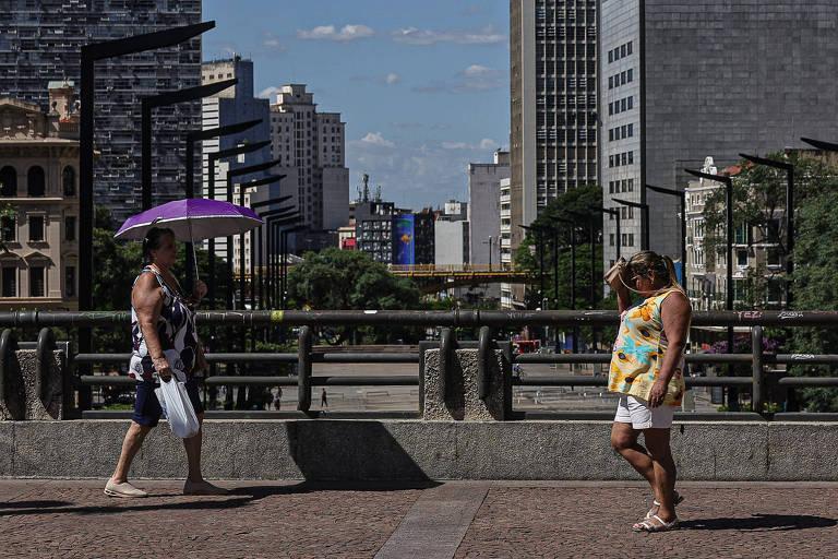 Mulheres se protegem do sol em área urbana