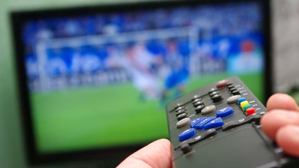Controle remoto, televisão e futebol.