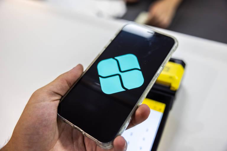 Mão segurando smartphone exibindo logotipo do Pagamento