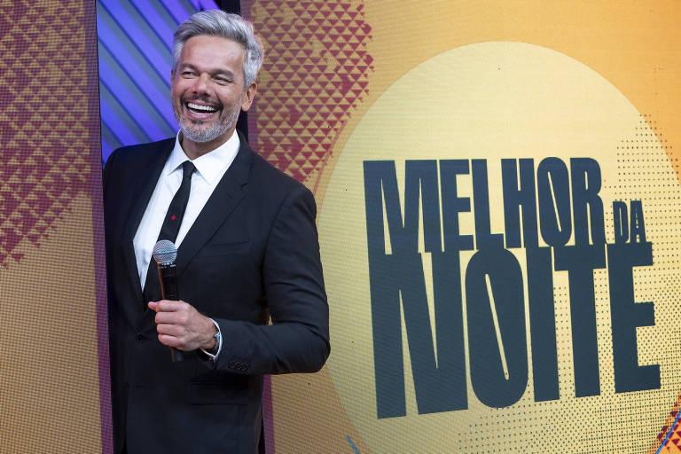 Otaviano Costa em um palco com o microfone