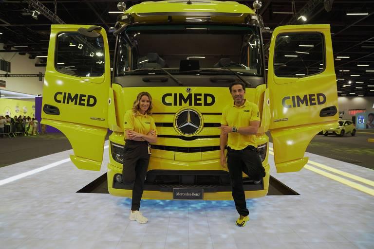 Caminhão da Cimed em evento, com dois representantes ao lado