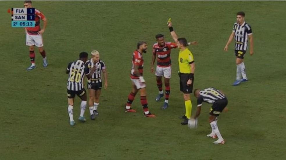 Os atacantes Gabigol e Bruno Henrique reclamam com o juiz Rafael Klein; apenas Gabigol recebe o amarelo.