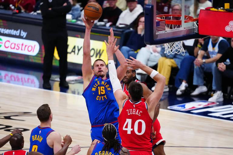 Jogador de basquete fazendo arremesso, cercado por outros jogadores.