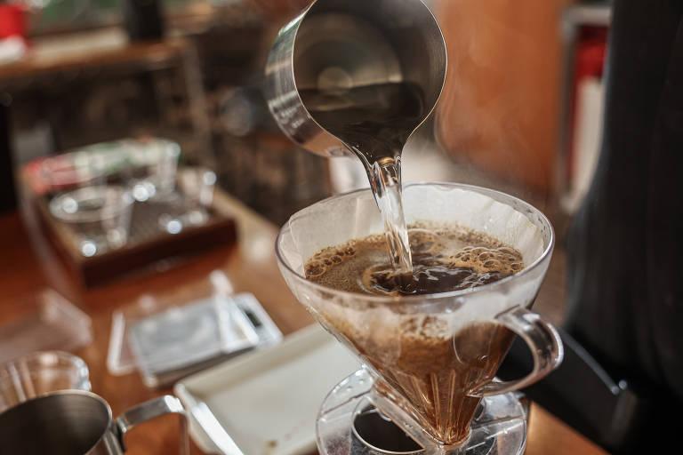 Jarra de alumínio despejando água sobre um coador de café