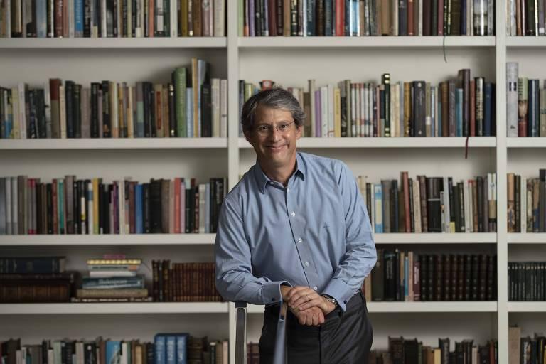 José Roberto de Castro Neves em sua biblioteca, com estante cheia de livros