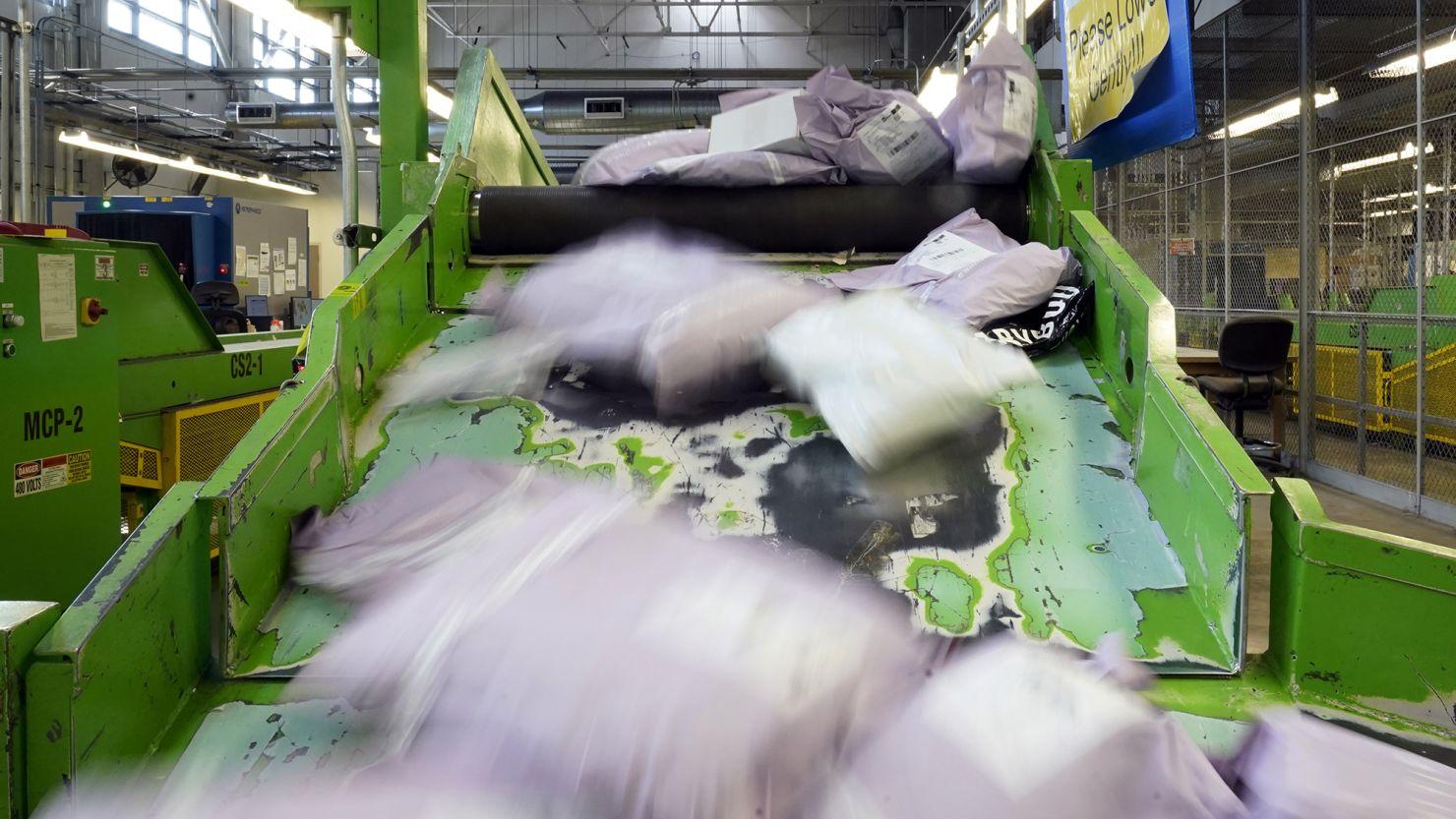 Pacotes descendo uma rampa após serem escaneados na instalação de inspeção do correio em Chicago.