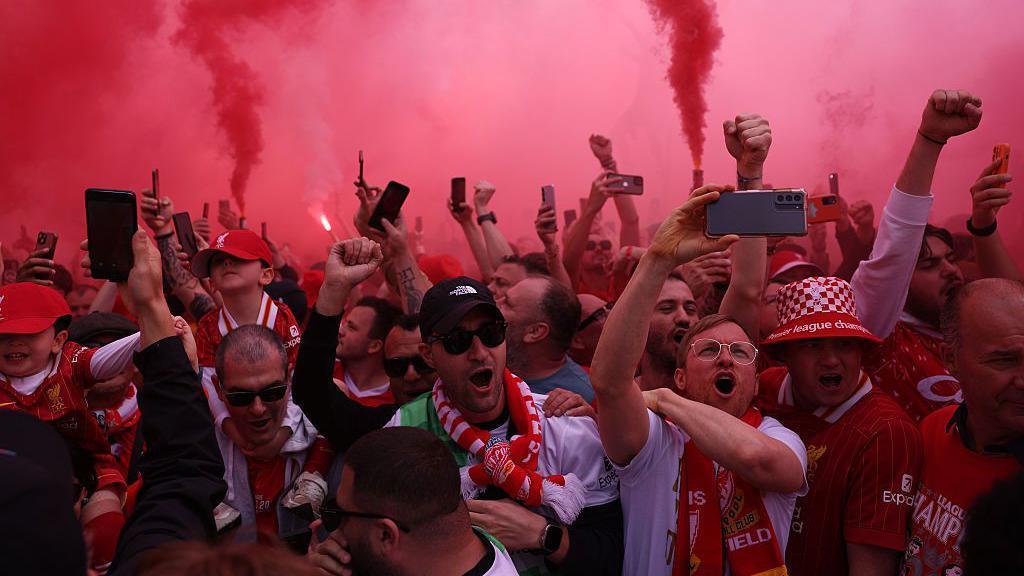 Image showing the streets around Anfield packed with supporters as red smoke flares fill the air
