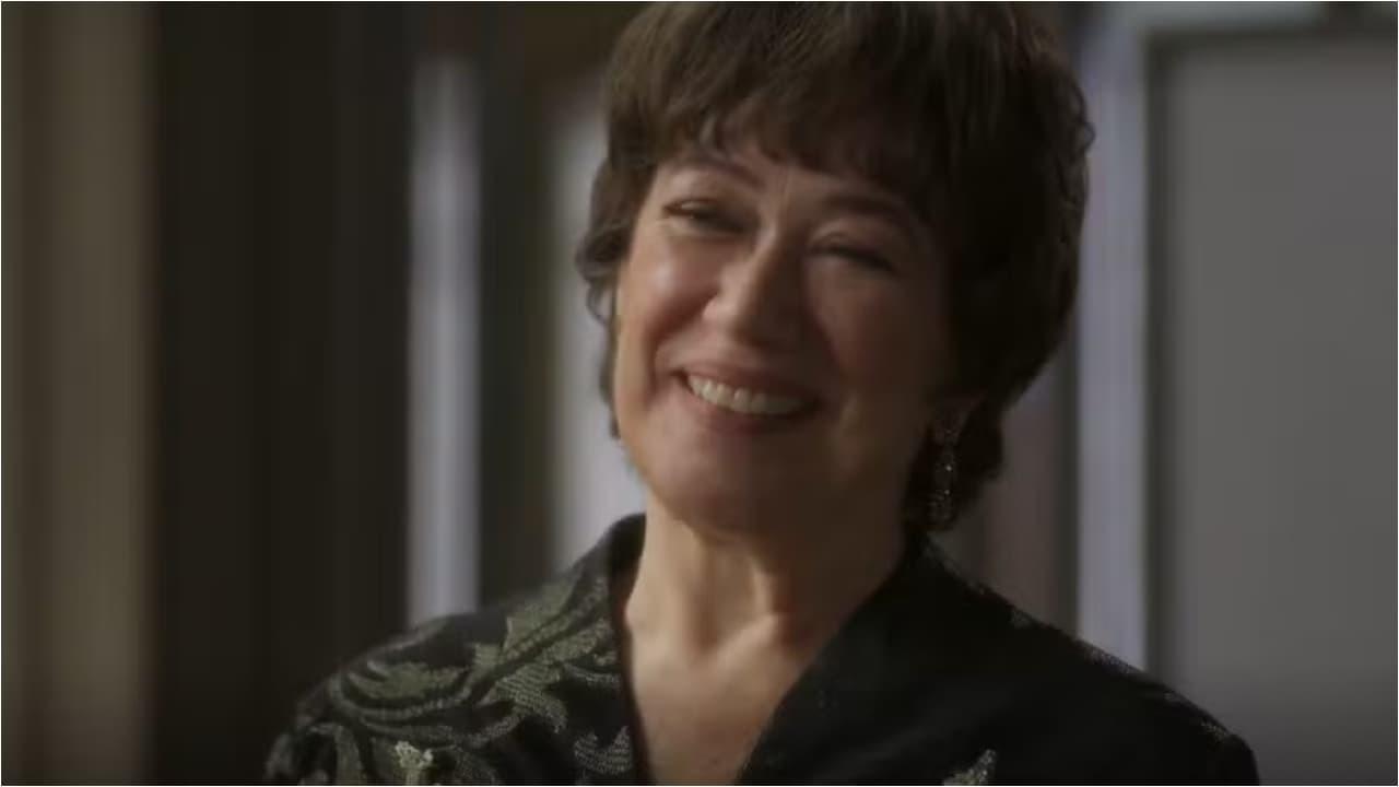 Lilia Cabral como Maristela de Garota do Momento, sorrindo, de roupa escura.