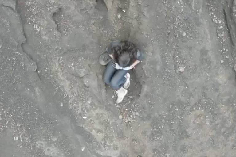 Imagem mostra uma pessoa sentada em uma área rochosa