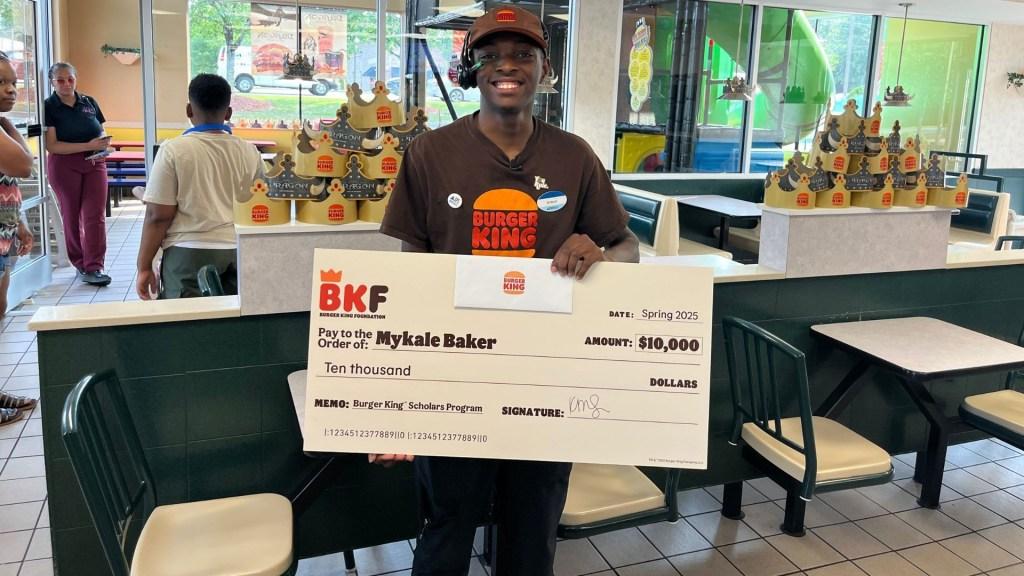 Mykale Baker, funcionário do Burger King, segurando um cheque de bolsa de $10,000.
