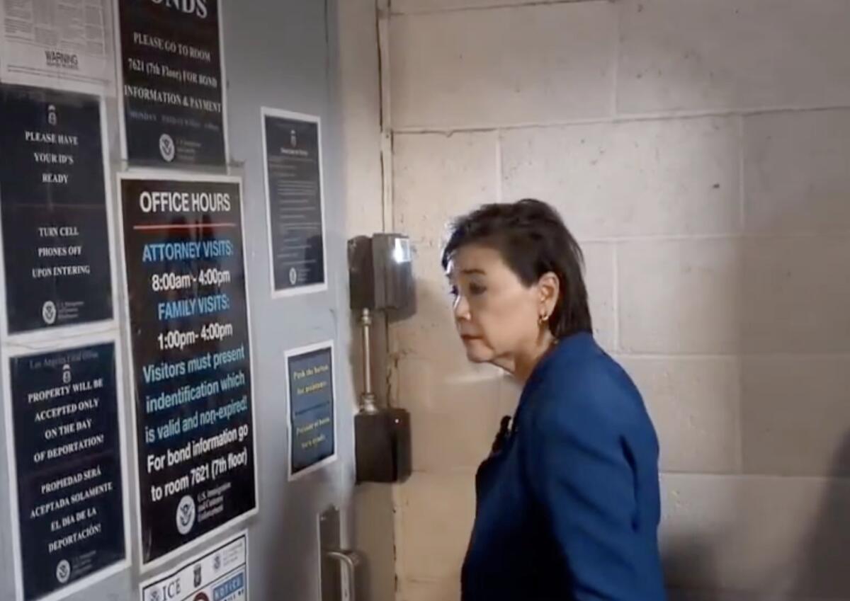 Rep. Judy Chu stands in front of a locked door holding various signs; one says 'office hours'.