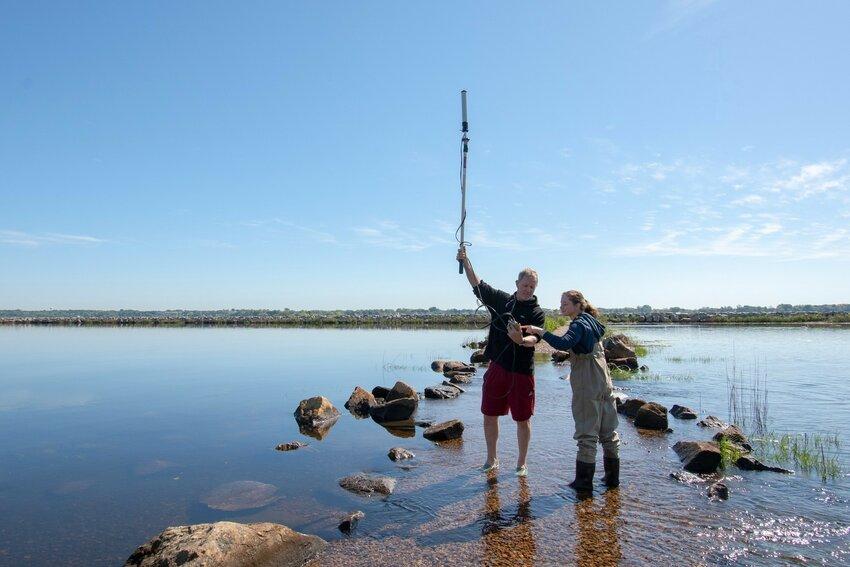 Dr. Brian Prendergast e Heather Kinney tentando obter um sinal de satélite na passagem coberta pela maré em Salter Grove, Warwick.