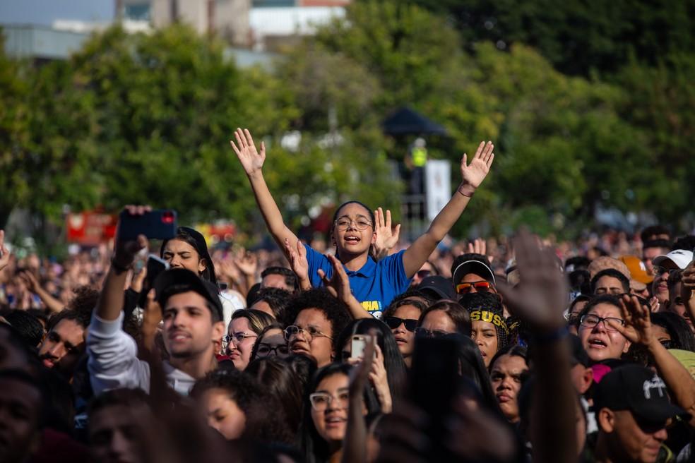 Jovem ergue os braços durante apresentação na Marcha para Jesus.