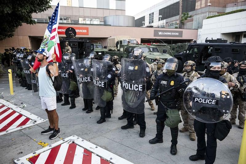 Um manifestante empunha uma bandeira mexicana-americana do lado de fora do Edifício Federal em Los Angeles.