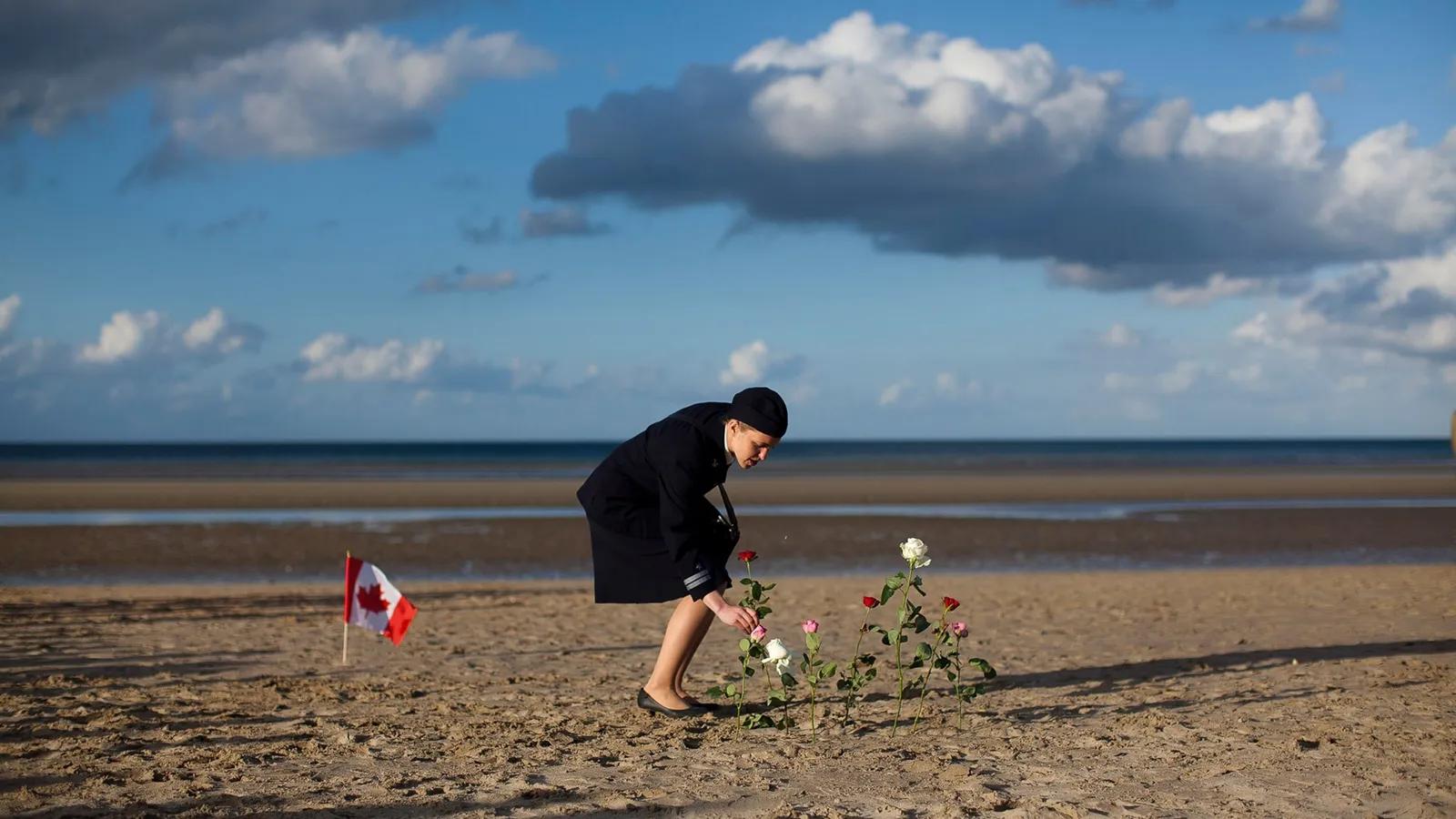 Uma mulher, em homenagem aos mortos na Segunda Guerra Mundial, coloca flores nas areias da praia
