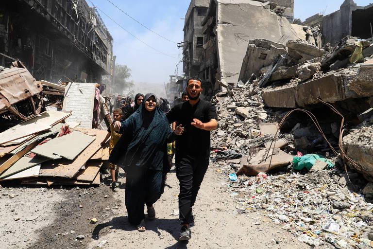 Cena de destruição em Gaza com pessoas correndo em emergência.