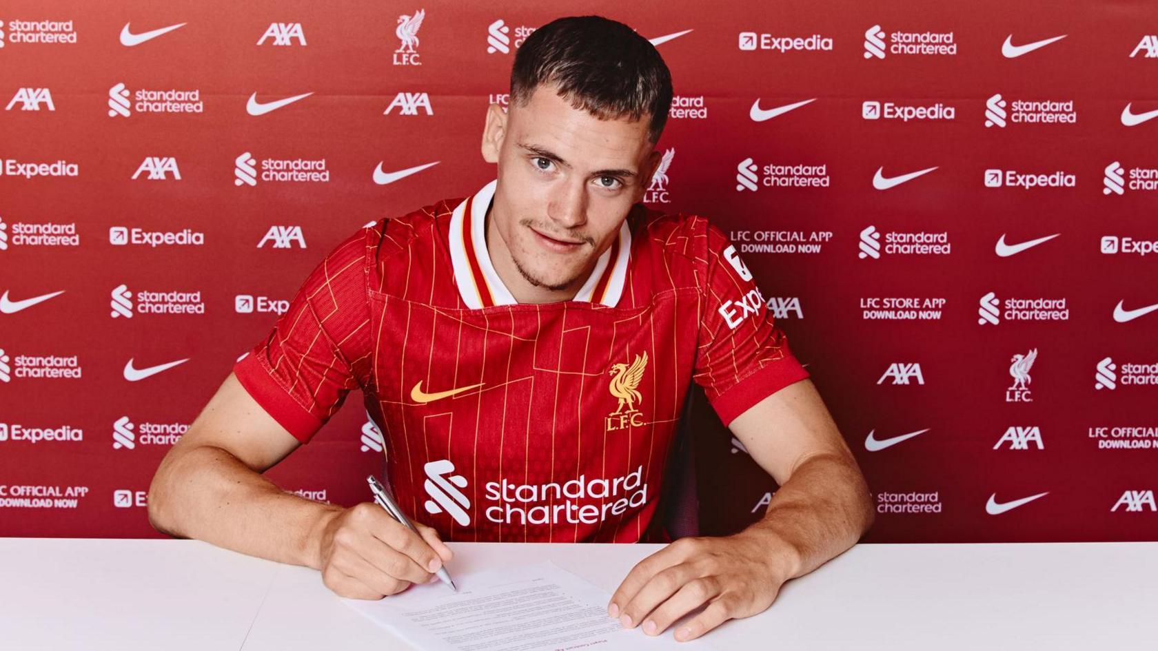 Florian Wirtz wearing a Liverpool shirt while signing his contract