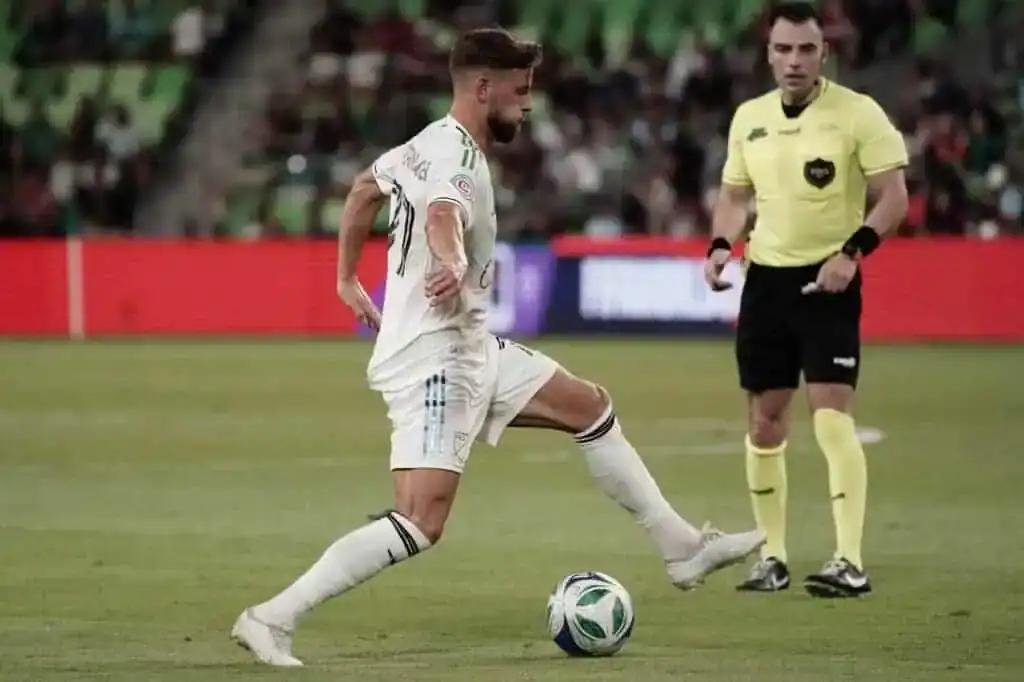 Jogador de futebol driblando a bola em campo