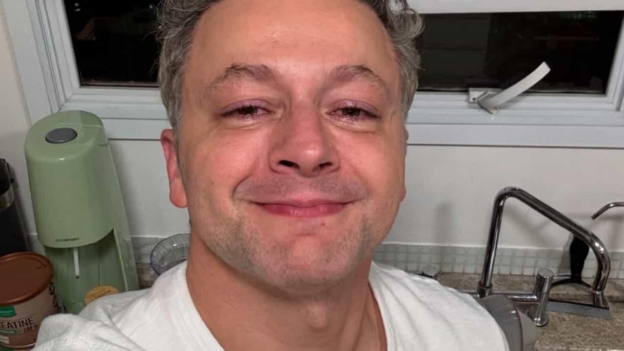 Lucas Lima em selfie com cara de choro, de camiseta branca, na cozinha