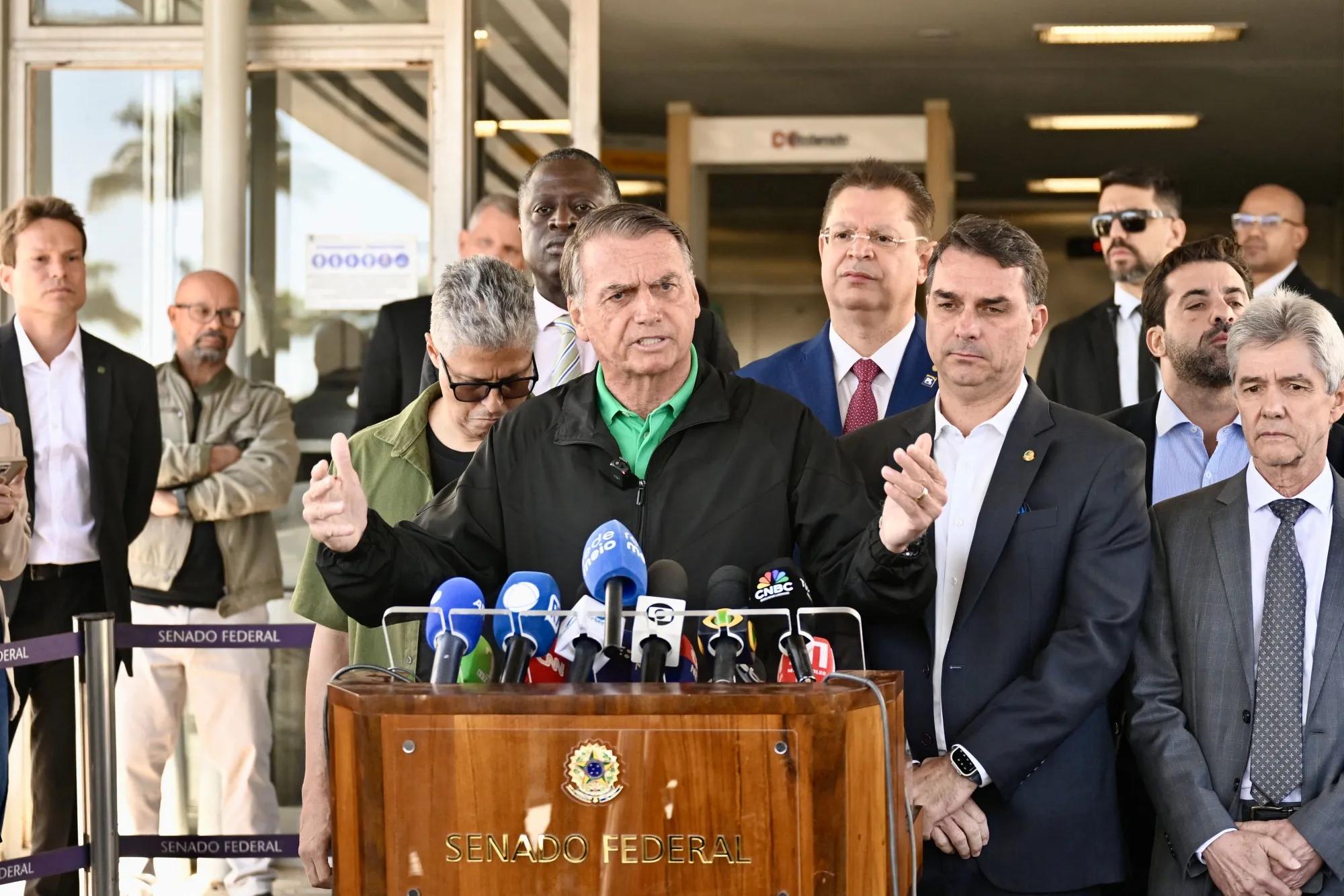 Jair Bolsonaro fala à imprensa com seu filho, o senador Flavio Bolsonaro, em Brasília.