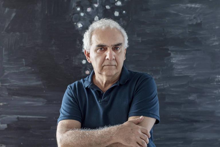 Milton Hatoum em frente a uma parede de arte abstrata