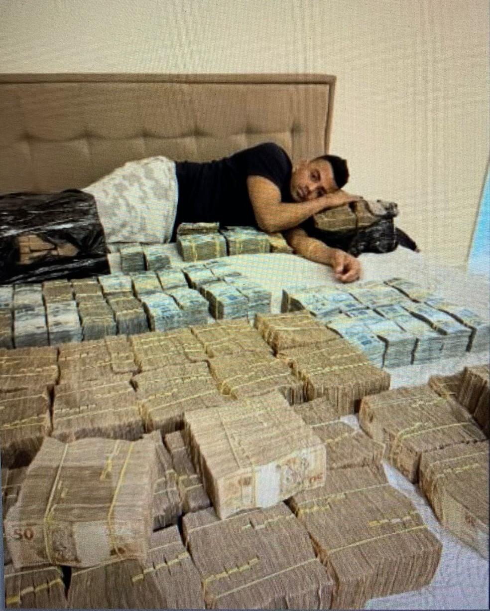 TH Joias deitado numa cama com maços de reais; PF suspeita que que valor seja de R$ 5 milhões