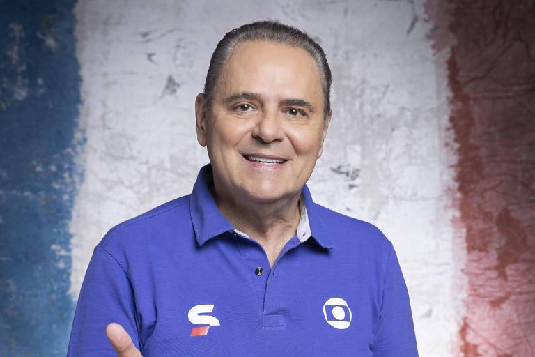 Homem sorridente posicionado em frente à bandeira da França